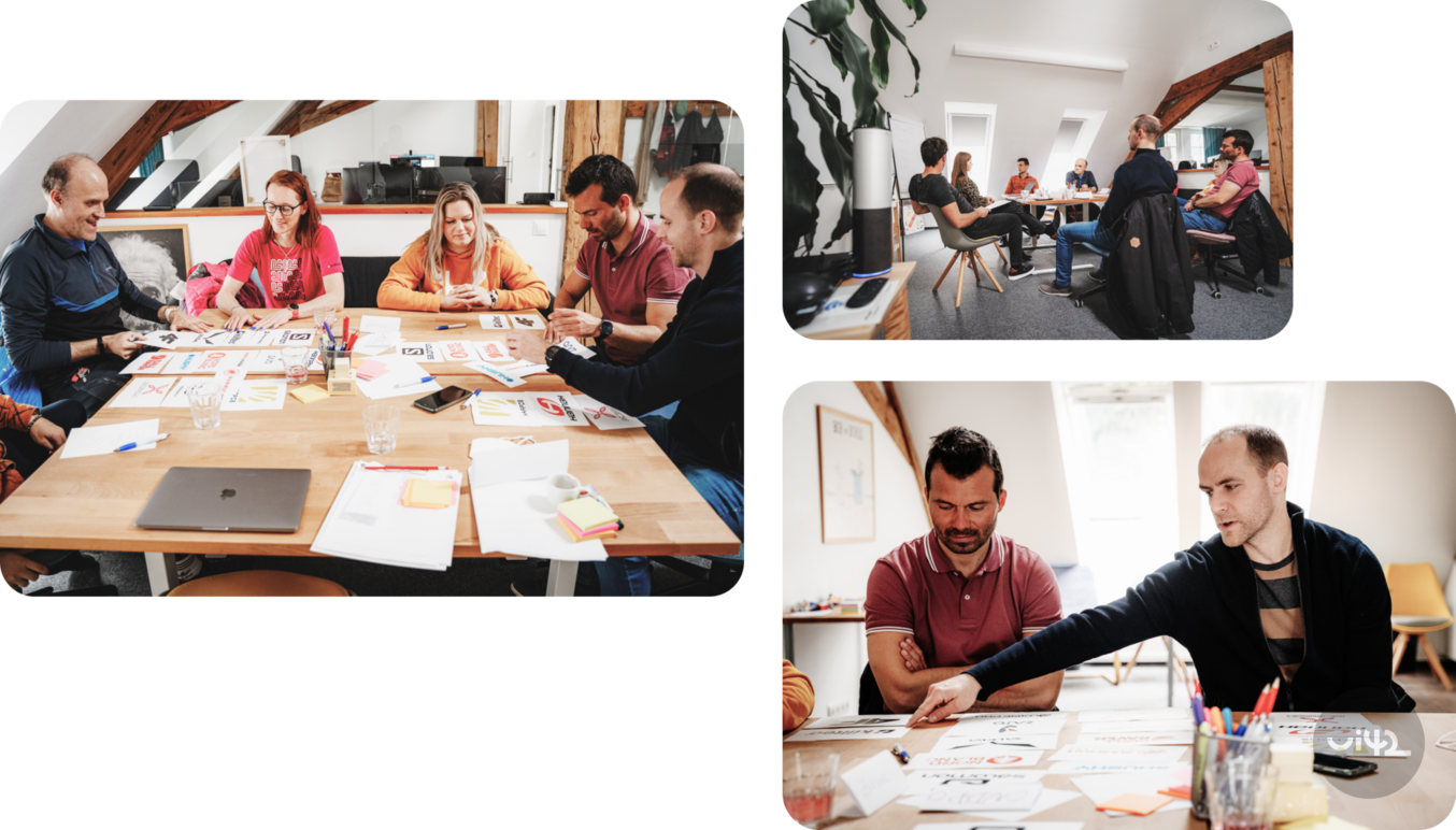 A group of people at the workshop is discussing various proposals and materials on the table.